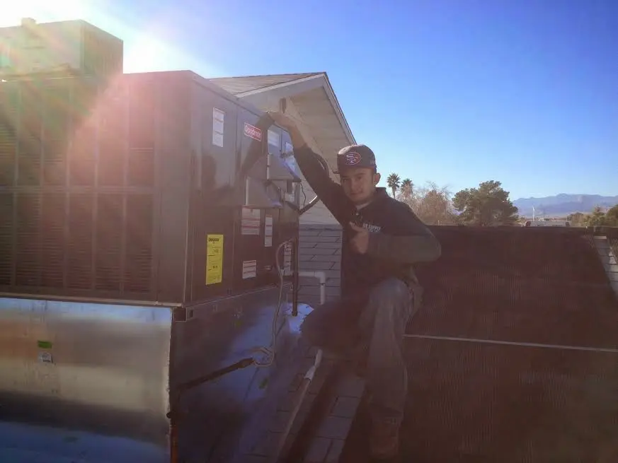 HVAC technician performing Air Duct Cleaning on a rooftop unit in East Peoria